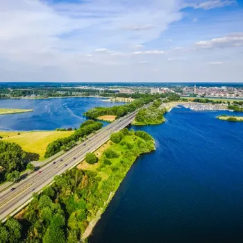 Luchtfoto van de Maasplassen bij Roermond, met brug, vaarwater en groene oevers op een heldere dag.